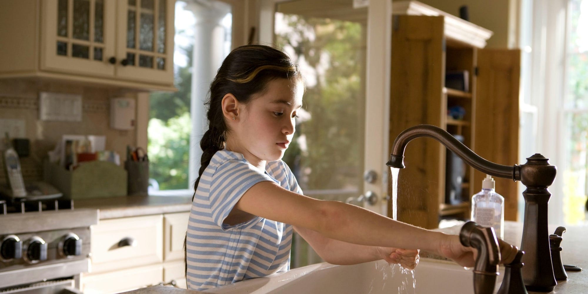 woman in blue and white stripe shirt washing her hands